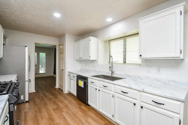 16323 Elmwood Point Ln, Sugar Land, TX 77498 - kitchen with dishwashing machine, a sink, black gas range oven, white cabinets, and backsplash