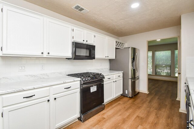 16323 Elmwood Point Ln, Sugar Land, TX 77498 - kitchen with appliances with stainless steel finishes, white cabinets, light wood-type flooring, a textured ceiling, and backsplash