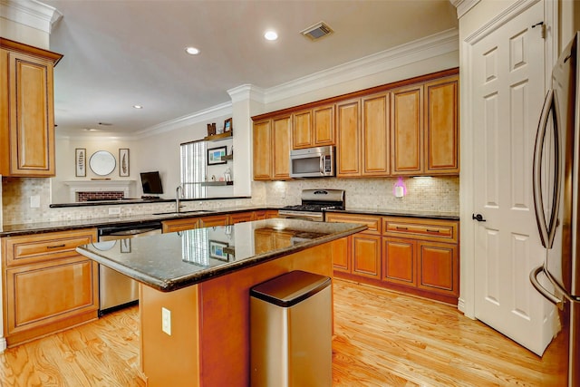 1529 Rosewood St, Houston, TX 77004 - kitchen featuring appliances with stainless steel finishes, a sink, light wood-style floors, a kitchen island, and crown molding
