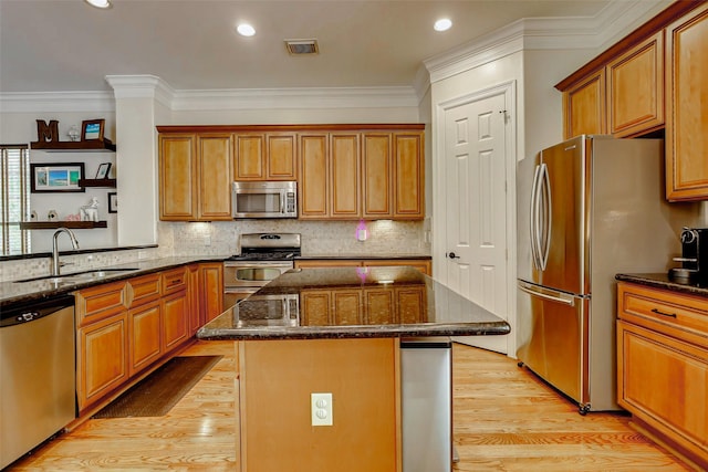 1529 Rosewood St, Houston, TX 77004 - kitchen with appliances with stainless steel finishes, a sink, a kitchen island, light wood-style floors, and dark stone counters