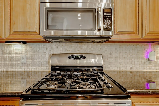 1529 Rosewood St, Houston, TX 77004 - kitchen featuring stainless steel microwave, range with gas stovetop, decorative backsplash, and dark countertops
