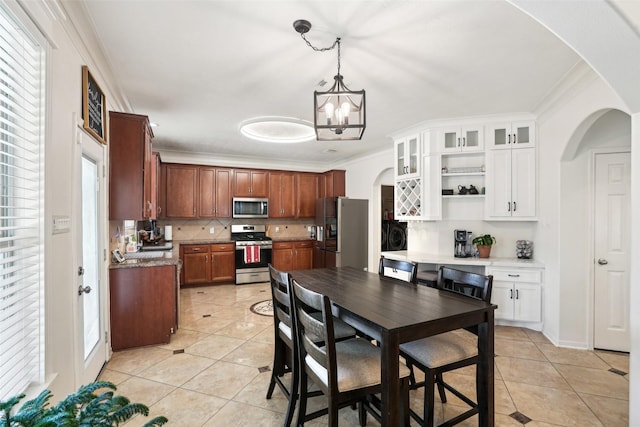 14 Carmel Chase Ct, Manvel, TX 77578 - kitchen featuring appliances with stainless steel finishes, arched walkways, decorative backsplash, light tile patterned flooring, and ornamental molding