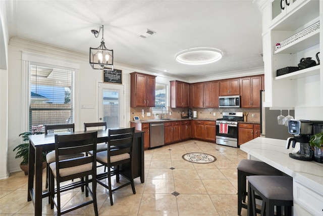 14 Carmel Chase Ct, Manvel, TX 77578 - kitchen with stainless steel appliances, light tile patterned flooring, a sink, decorative backsplash, and ornamental molding