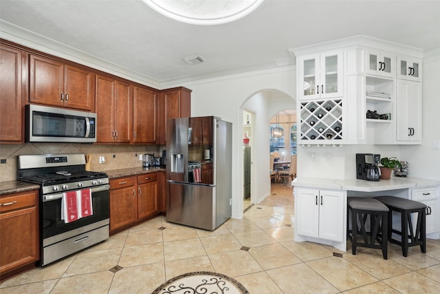 14 Carmel Chase Ct, Manvel, TX 77578 - kitchen with appliances with stainless steel finishes, arched walkways, ornamental molding, backsplash, and glass insert cabinets