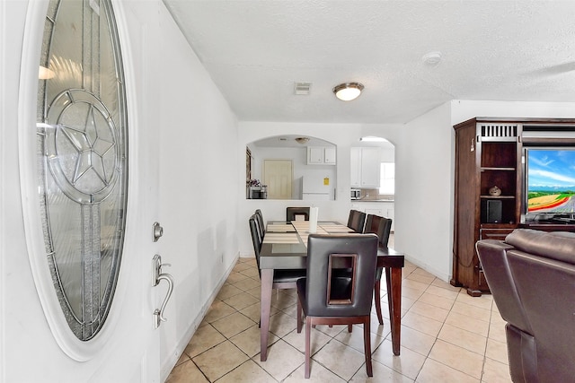 1607 Beusch Dr, Pasadena, TX 77502 - dining room with arched walkways, light tile patterned floors, a textured ceiling, and baseboards