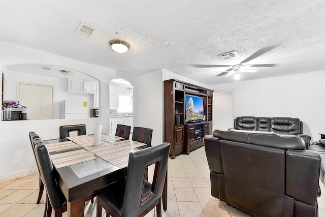 1607 Beusch Dr, Pasadena, TX 77502 - dining room featuring light tile patterned floors, arched walkways, ceiling fan, and a textured ceiling