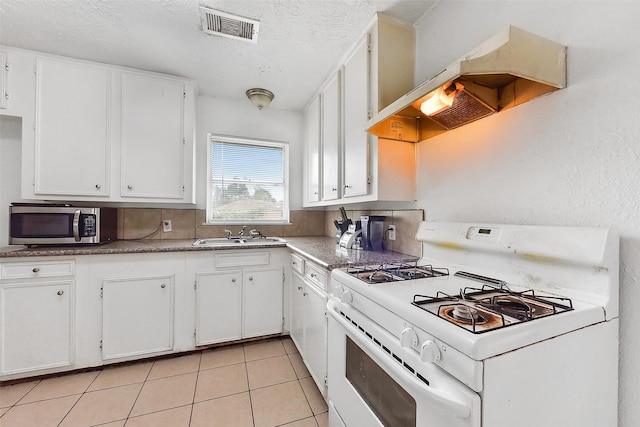 1607 Beusch Dr, Pasadena, TX 77502 - kitchen with white gas range, custom exhaust hood, stainless steel microwave, a sink, and white cabinetry