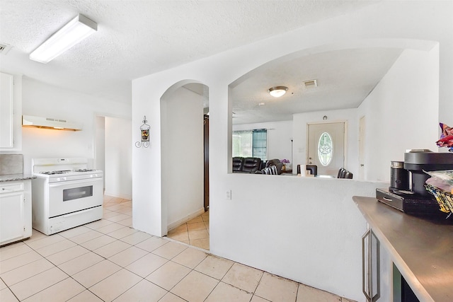 1607 Beusch Dr, Pasadena, TX 77502 - kitchen with gas range gas stove, under cabinet range hood, arched walkways, a textured ceiling, and white cabinets