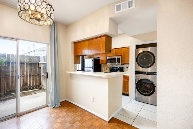 7575 Cambridge St Unit 1604, Houston, TX 77054 - kitchen featuring stainless steel microwave, freestanding refrigerator, stacked washer / drying machine, black / electric stove, and brown cabinetry