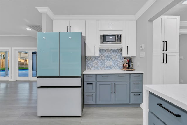 5122 Braesheather Dr, Houston, TX 77096 - kitchen featuring freestanding refrigerator, stainless steel microwave, light countertops, backsplash, and crown molding