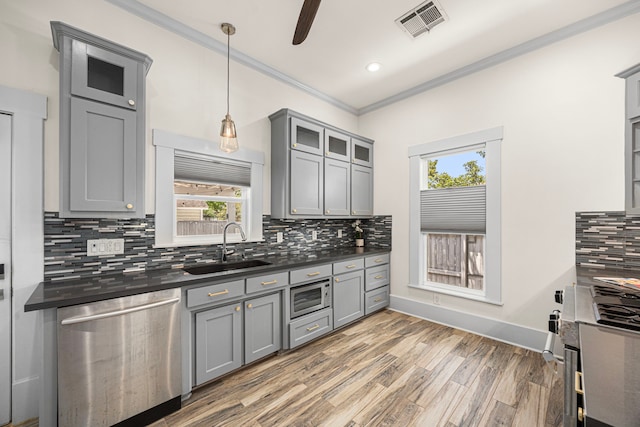 826 Omar St, Houston, TX 77009 - kitchen with stainless steel appliances, gray cabinetry, dark countertops, crown molding, and light wood-type flooring