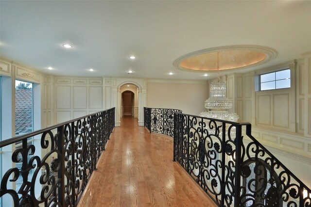 17122 Ashley Woods Ct, Spring, TX 77379 - hallway featuring arched walkways, a decorative wall, wood finished floors, an upstairs landing, and a chandelier