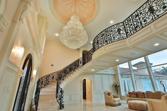 17122 Ashley Woods Ct, Spring, TX 77379 - stairway featuring a towering ceiling, a decorative wall, a chandelier, arched walkways, and recessed lighting