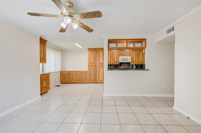 12028 Mighty Oak Dr Unit A, Houston, TX 77066 - kitchen featuring white microwave, crown molding, ceiling fan, a textured ceiling, and brown cabinets