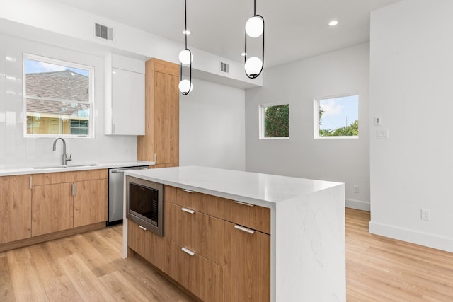 2312 Barbee St, Houston, TX 77004 - kitchen featuring a sink, light wood-style flooring, a center island, backsplash, and hanging light fixtures