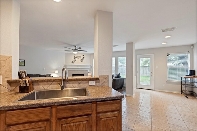 25430 Twister Trl, Spring, TX 77373 - kitchen featuring a sink, a fireplace, a ceiling fan, open floor plan, and brown cabinetry