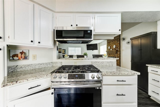11111 Clear Fork Dr, Humble, TX 77396 - kitchen featuring stainless steel appliances, white cabinets, a peninsula, light stone countertops, and brick wall