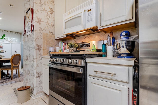 14639 Cypress Cottage Ct, Cypress, TX 77429 - kitchen featuring stainless steel appliances, wallpapered walls, light tile patterned floors, decorative backsplash, and white cabinets