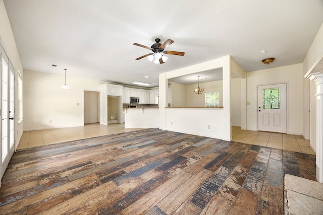 40614 Rolling Forest Dr, Magnolia, TX 77354 - unfurnished living room featuring ceiling fan, a chandelier, wood-type flooring, and baseboards