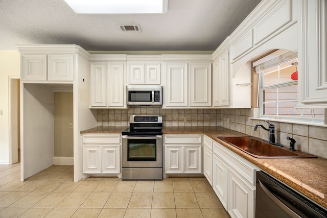 40614 Rolling Forest Dr, Magnolia, TX 77354 - kitchen with appliances with stainless steel finishes, a sink, backsplash, and white cabinets