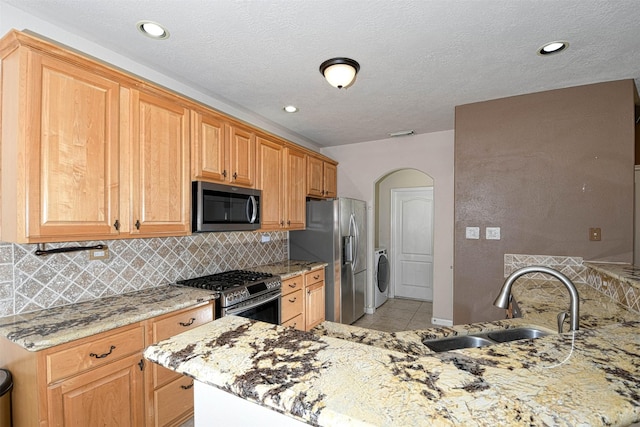 107 Cove W, Conroe, TX 77356 - kitchen featuring appliances with stainless steel finishes, washer / clothes dryer, decorative backsplash, light stone counters, and recessed lighting