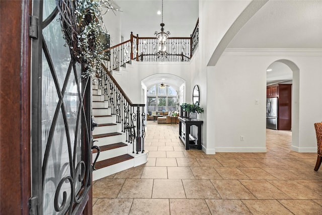 12415 Bunker Cove Dr, Cypress, TX 77433 - entrance foyer with arched walkways, a chandelier, baseboards, crown molding, and stairs