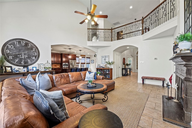 12415 Bunker Cove Dr, Cypress, TX 77433 - living area featuring arched walkways, ceiling fan, a high ceiling, baseboards, and a fireplace with raised hearth