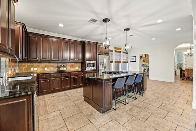 12415 Bunker Cove Dr, Cypress, TX 77433 - kitchen with stainless steel appliances, a sink, arched walkways, a chandelier, and backsplash