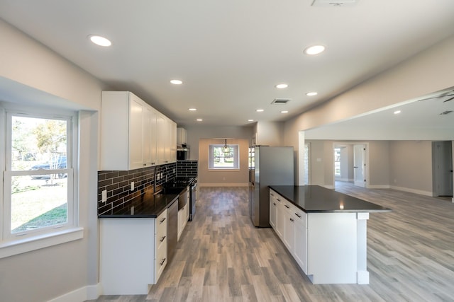 9219 Pecos St, Houston, TX 77055 - kitchen featuring baseboards, dark countertops, stainless steel appliances, white cabinets, and tasteful backsplash