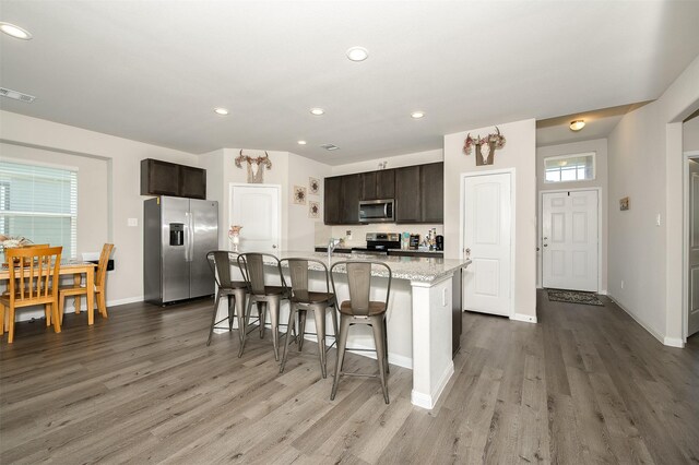 5766 Cerrillos Dr, Bryan, TX 77807 - kitchen with stainless steel appliances, wood finished floors, baseboards, a kitchen island with sink, and recessed lighting