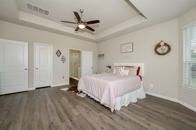 5766 Cerrillos Dr, Bryan, TX 77807 - bedroom featuring a tray ceiling, wood finished floors, baseboards, and multiple windows