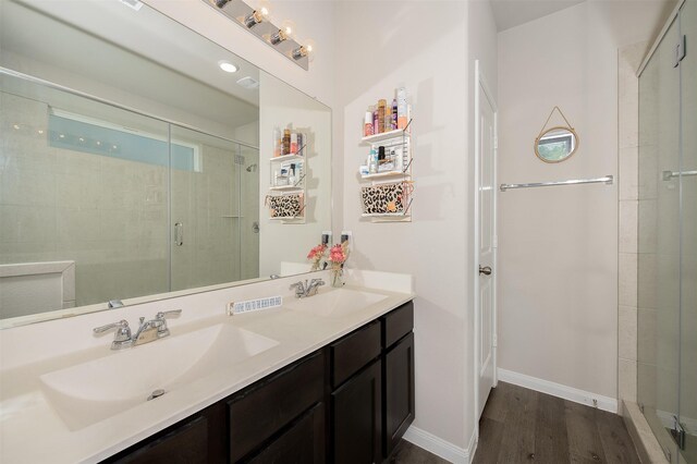 5766 Cerrillos Dr, Bryan, TX 77807 - bathroom with wood finished floors, a stall shower, double vanity, and baseboards