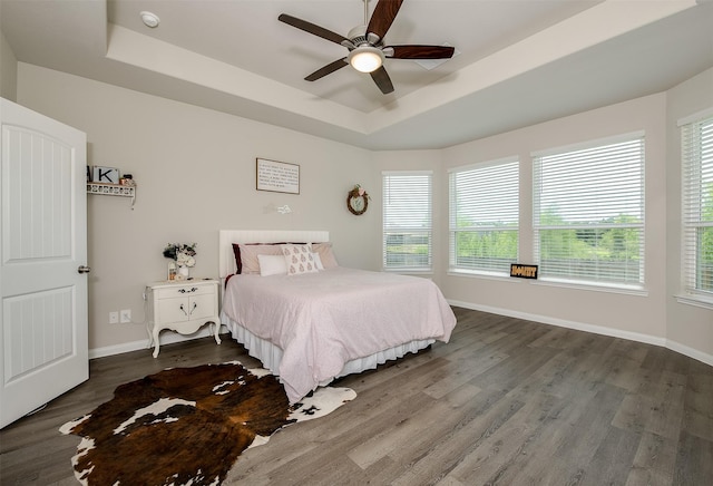 5766 Cerrillos Dr, Bryan, TX 77807 - bedroom featuring a raised ceiling, baseboards, dark wood-type flooring, and a ceiling fan