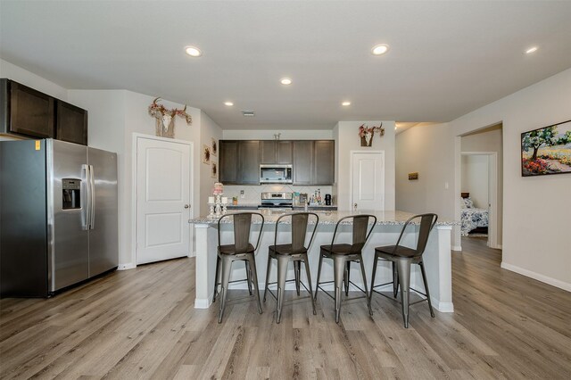 5766 Cerrillos Dr, Bryan, TX 77807 - kitchen featuring appliances with stainless steel finishes, light wood-style floors, baseboards, dark brown cabinetry, and recessed lighting