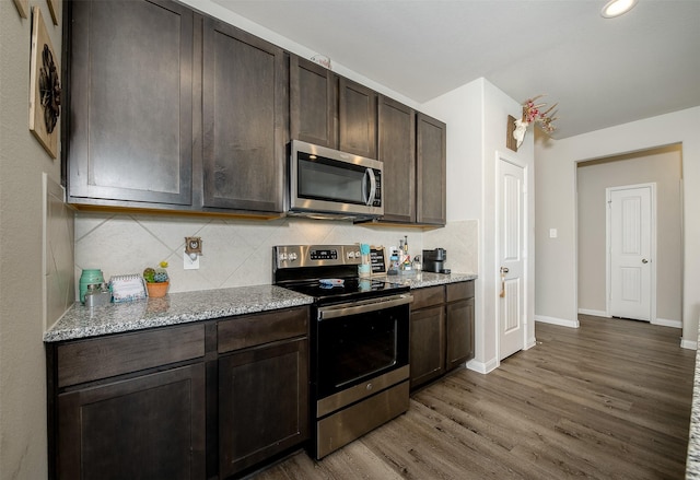 5766 Cerrillos Dr, Bryan, TX 77807 - kitchen featuring appliances with stainless steel finishes, wood finished floors, dark brown cabinets, tasteful backsplash, and baseboards