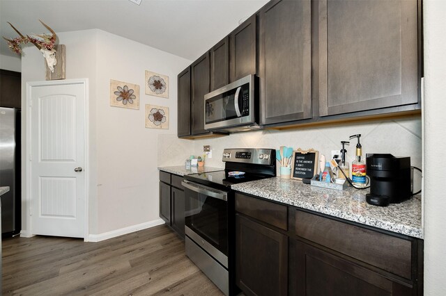 5766 Cerrillos Dr, Bryan, TX 77807 - kitchen with appliances with stainless steel finishes, dark wood-style floors, dark brown cabinetry, and light stone countertops