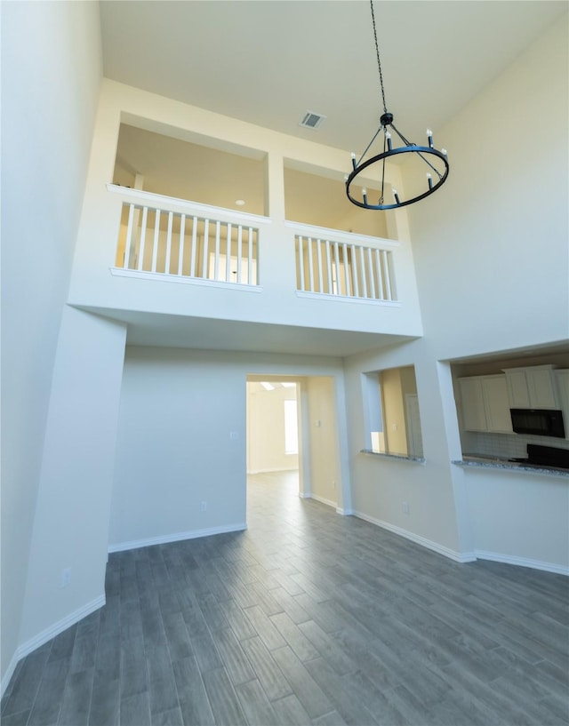 40575 Goldeneye Pl, Magnolia, TX 77354 - unfurnished living room with a chandelier, dark wood-style floors, a high ceiling, and baseboards