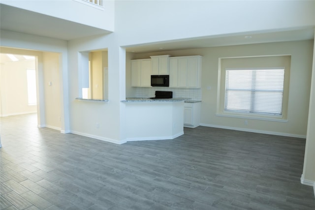 40575 Goldeneye Pl, Magnolia, TX 77354 - kitchen featuring black microwave, stove, white cabinets, and baseboards