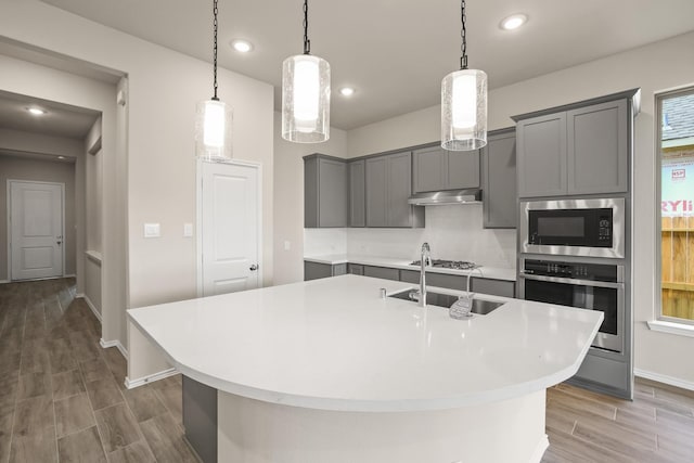 1963 Waters Branch Dr, Missouri City, TX 77459 - kitchen with stainless steel appliances, gray cabinetry, a sink, decorative backsplash, and light countertops