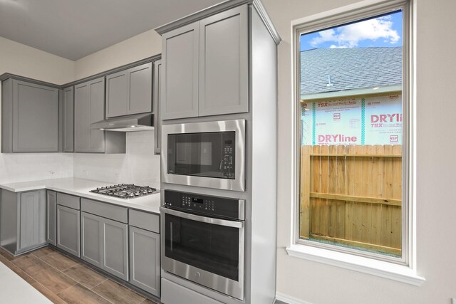 1963 Waters Branch Dr, Missouri City, TX 77459 - kitchen with appliances with stainless steel finishes, gray cabinets, under cabinet range hood, and light countertops