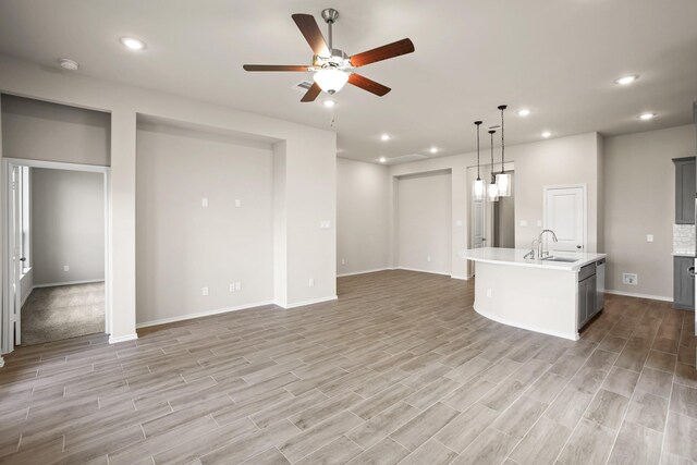 1963 Waters Branch Dr, Missouri City, TX 77459 - unfurnished living room with ceiling fan, a sink, light wood-style flooring, baseboards, and recessed lighting