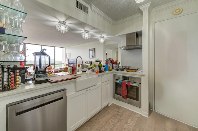 5001 Woodway Dr Unit 1405, Houston, TX 77056 - kitchen with stainless steel appliances, wall chimney exhaust hood, ornamental molding, light wood-style floors, and light countertops