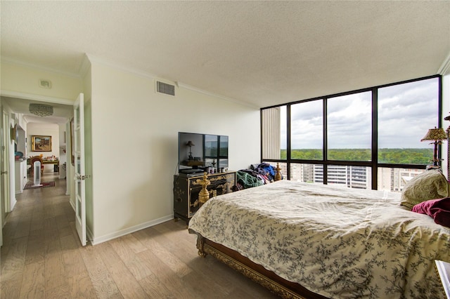 5001 Woodway Dr Unit 1405, Houston, TX 77056 - bedroom featuring light wood-type flooring, crown molding, a textured ceiling, baseboards, and expansive windows