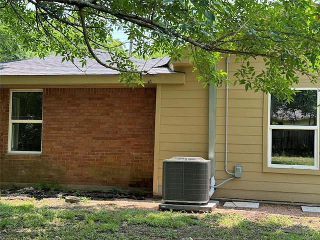 8117 Snowden St, Houston, TX 77028 - view of side of property with central air condition unit, brick siding, and roof with shingles
