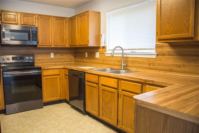 7331 Burkridge Dr, Houston, TX 77041 - kitchen featuring stainless steel appliances, wooden counters, a sink, brown cabinets, and light flooring