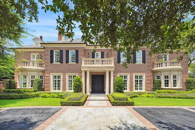 24 Farnham Park Dr, Houston, TX 77024 - georgian-style home featuring a balcony, brick siding, a chimney, and a front lawn
