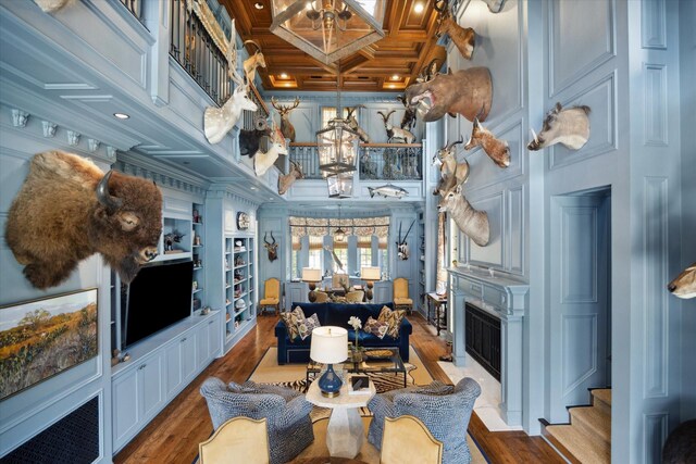 24 Farnham Park Dr, Houston, TX 77024 - living room with a chandelier, a fireplace with flush hearth, wood finished floors, coffered ceiling, and ornamental molding