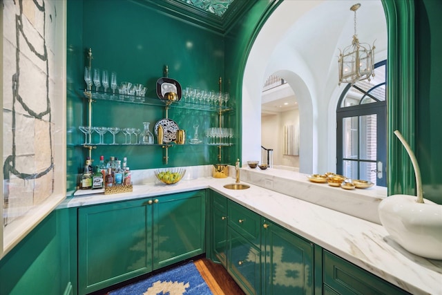 24 Farnham Park Dr, Houston, TX 77024 - indoor wet bar featuring a chandelier, arched walkways, crown molding, and dark wood-style floors