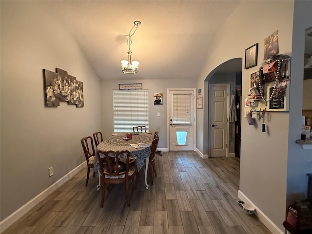 207 Leisure Ln, Montgomery, TX 77356 - dining room with lofted ceiling, arched walkways, dark wood-type flooring, a chandelier, and baseboards