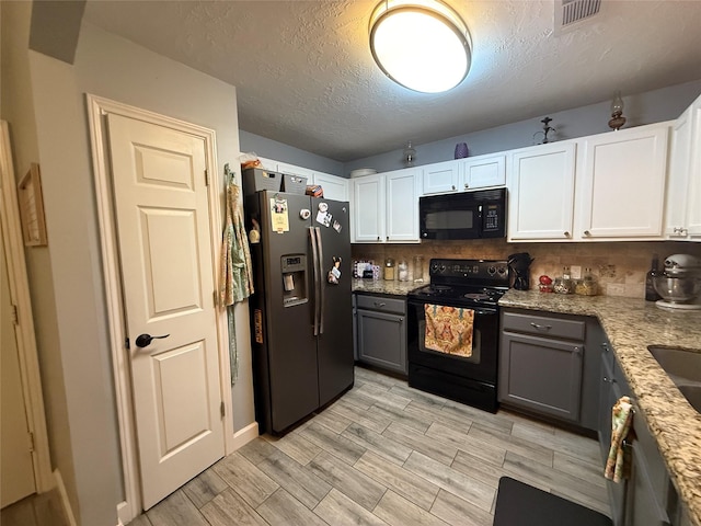207 Leisure Ln, Montgomery, TX 77356 - kitchen featuring black appliances, white cabinets, light stone counters, a textured ceiling, and wood tiled floors